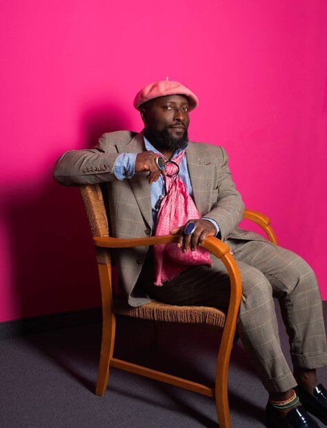 Prof. Dr. Bonaventure Soh Bejeng Ndikun seats in a chair, with a pink wall as background